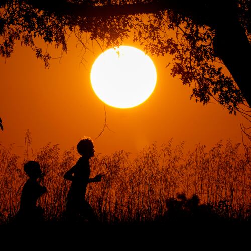 FILE - People are silhouetted against the sky at sunset as they run at Shawnee Mission Park, Sept. 26, 2024, in Shawnee, Kan. (AP Photo/Charlie Riedel, File)