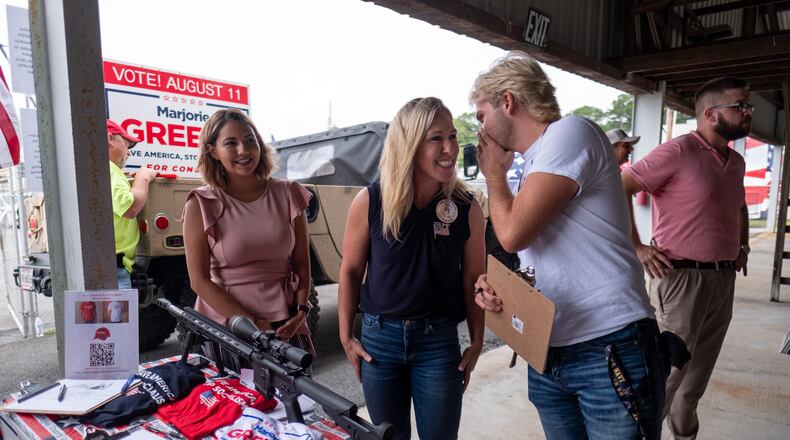 200829-Rome- Marjorie Taylor Greene, center, a Republican running to represent Georgia’s 14th congressional district, listens to Joshua Abernathy as he prepares to fill out a form to be entered into a drawing for an assault-style riffle as a fundraiser for Greene during a political rally at the Rome fairgrounds Saturday morning August 29, 2020. Greene used the riffle in a campaign aid where she shoots and blows up the Green New Deal, gun control, socialism and open borders.  Ben Gray for the Atlanta Journal-Constitution