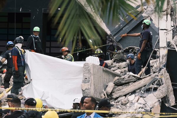 Rescue workers use sheets as they recover bodies from the rubble at the Jet Set nightclub after its roof collapsed two nights prior during a merengue concert in Santo Domingo, Dominican Republic, Wednesday, April 9, 2025. (AP Photo/Ricardo Hernandez)