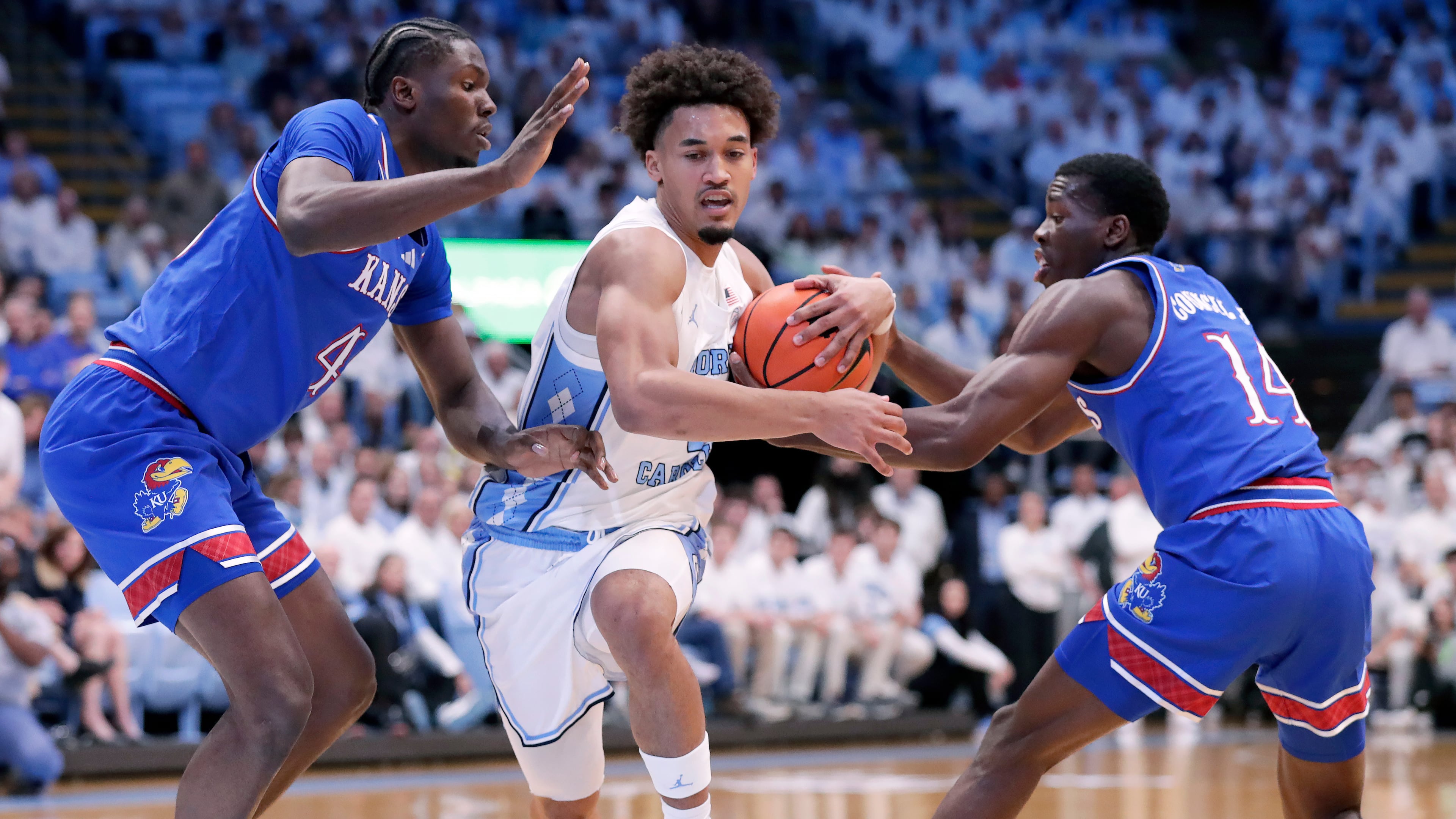 North Carolina guard Seth Trimble, center, drives between Kansas forward Flory Bidunga, left, and guard Melvin Council Jr. (14) during the first half of an NCAA college basketball game Friday, Nov. 7, 2025, in Chapel Hill, N.C. (AP Photo/Chris Seward)