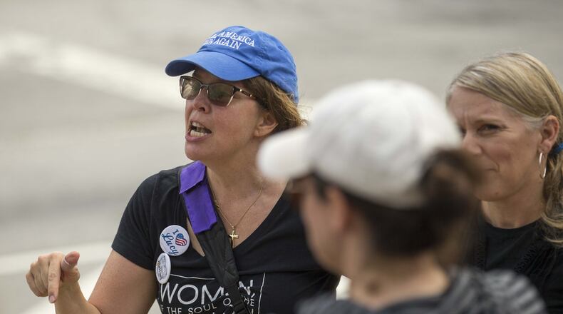 No Safe Seats member Jenny Peterson, left, speaks to a group of women gathered Friday outside U.S. Sen. Johnny Isakson’s Atlanta-area office to protest the nomination of Brett Kavanaugh to the U.S. Supreme Court. (ALYSSA POINTER/ALYSSA.POINTER@AJC.COM)