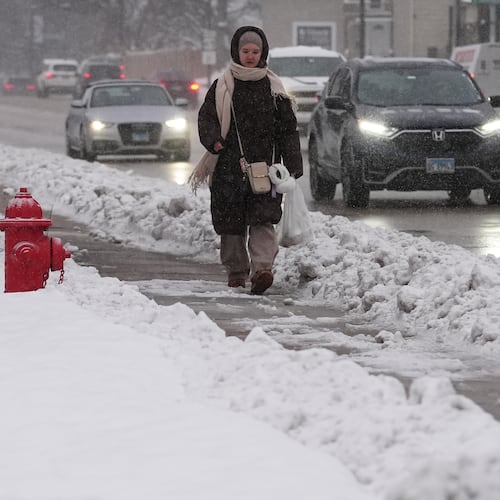 A pedestrian walks on a snow-covered sidewalk in Wheeling, Ill., Monday, Dec. 1, 2025. (AP Photo/Nam Y. Huh)