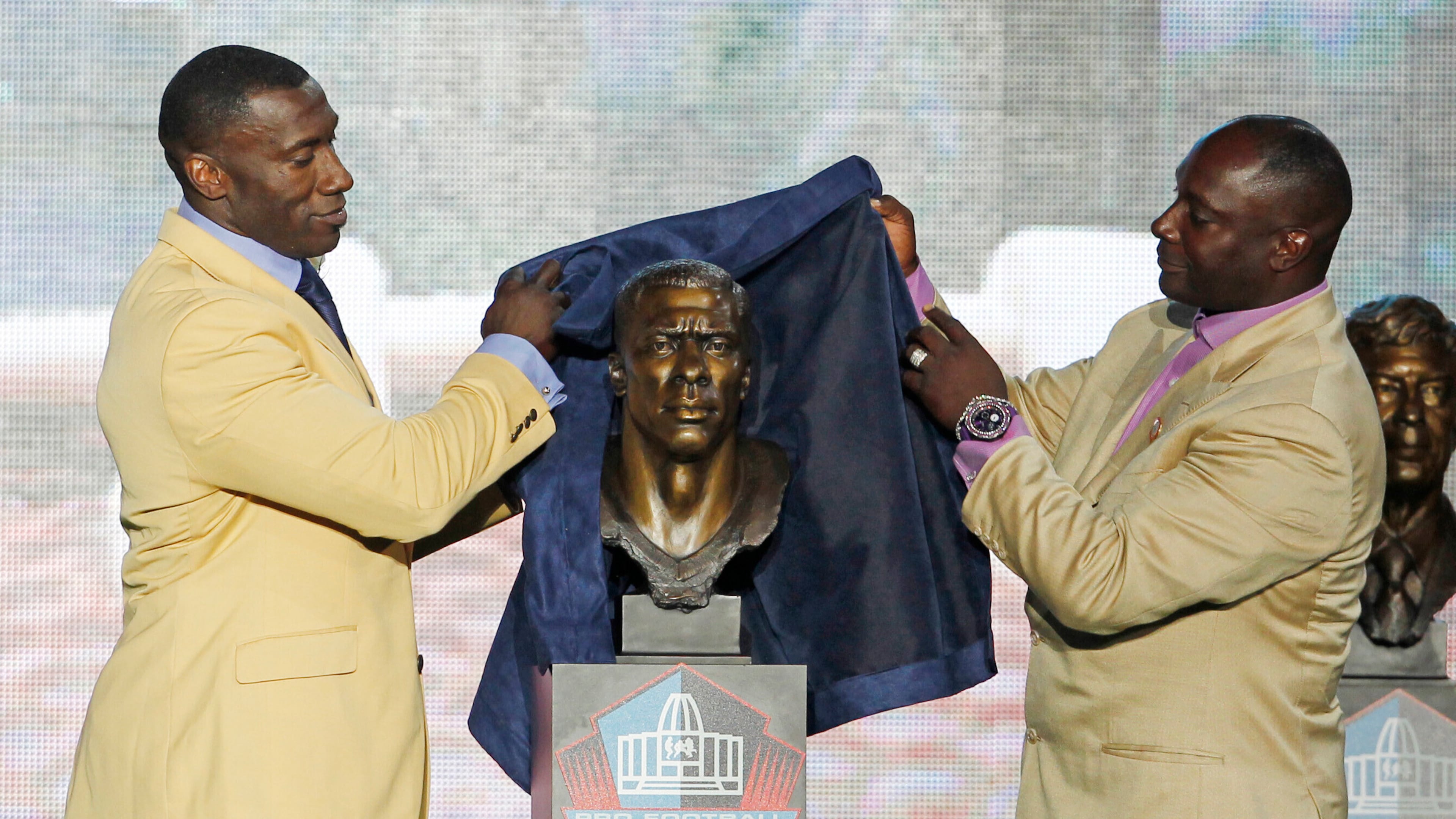 Shannon Sharpe (left) unveils a bust of himself along with his presenter and brother, Sterling Sharpe, during his induction ceremony at the Pro Football Hall of Fame on Saturday, Aug. 6, 2011, in Canton, Ohio. On Saturday, Aug, 2, 2025, Sterling was inducted into the Hall of Fame alongside his brother. (Ron Schwane/AP 2011)