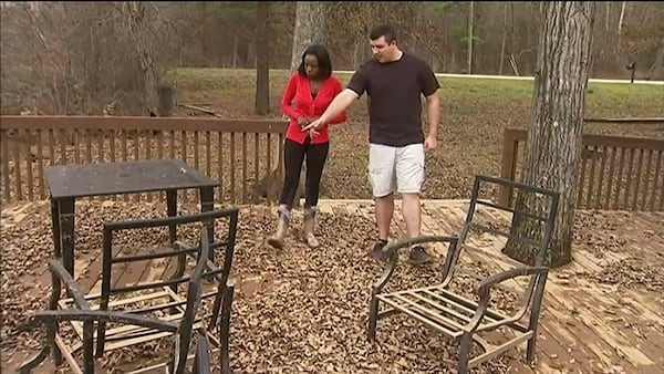 Nathan Bradley (right) shows Channel 2’s Audrey Washington the patio furniture covered in mud and other debris from flooding in 2020. (Courtesy of Channel 2 Action News)