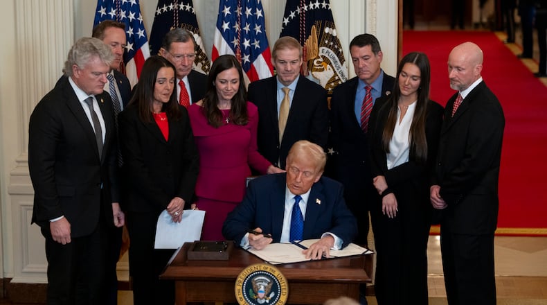 President Donald Trump, surrounded by members of Congress and Laken Riley’s family, signs the Laken Riley Act on Jan. 29. (Nathan Posner for the AJC)