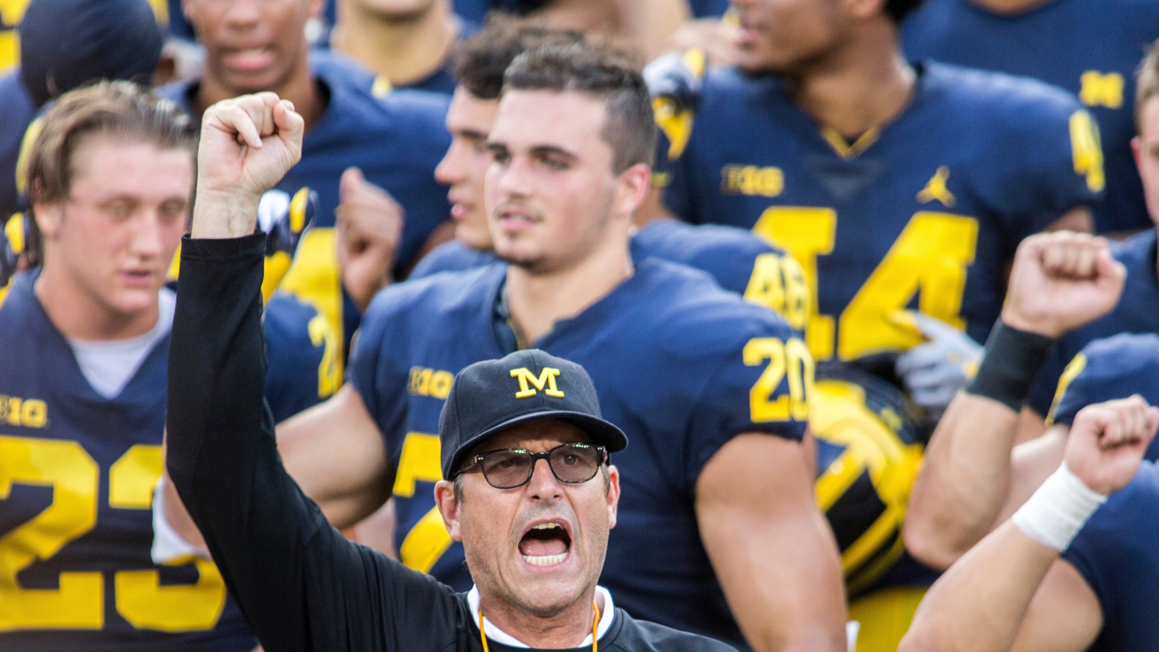 FILE - In this Aug. 26, 2018, file photo, Michigan head coach Jim Harbaugh leads his players and fans in singing "Hail to the Victors" after a practice session by the NCAA college football team at Michigan Stadium in Ann Arbor, Mich..(AP Photo/Tony Ding, File)