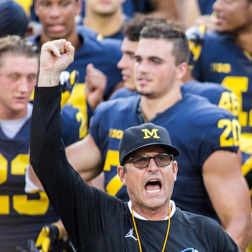 FILE - In this Aug. 26, 2018, file photo, Michigan head coach Jim Harbaugh leads his players and fans in singing "Hail to the Victors" after a practice session by the NCAA college football team at Michigan Stadium in Ann Arbor, Mich..(AP Photo/Tony Ding, File)