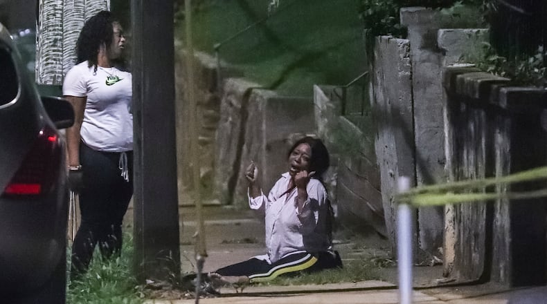 A distraught woman cries on the sidewalk along Sunset Avenue in northwest Atlanta after two people were killed and two others were injured on July 24, 2020, when gunfire erupted outside a house party in the Vine City neighborhood, authorities said. Rapper Raezion Boyd, who was 18 and went by Rae Rae, had just been signed to Motown Records. He was one of the victims shot to death outside the house party. (JOHN SPINK/JSPINK@AJC.COM)