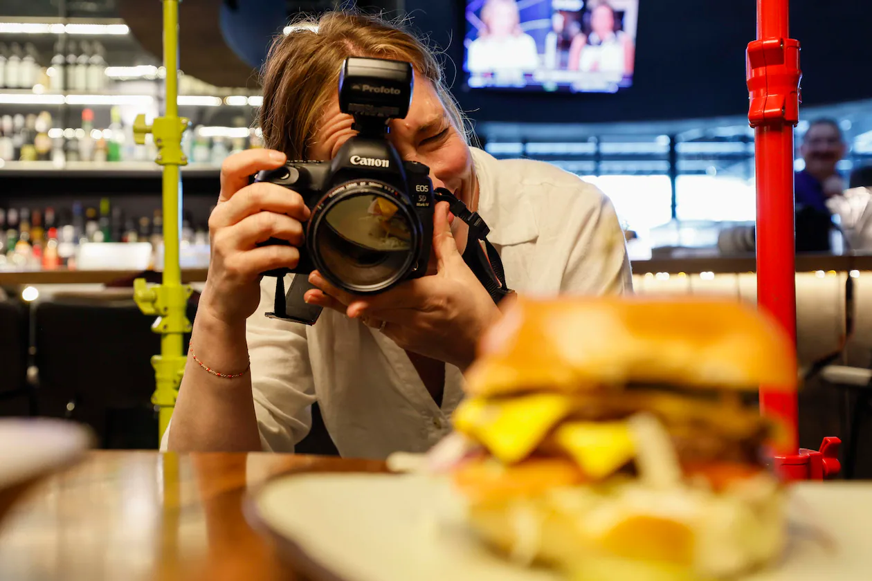 Atlanta-based lifestyle photographer Heidi Harris at work at the Painted Pickle, where she's using her own product: colorful light stands from her new company, Surrounded by Light. (Miguel Martinez/AJC)