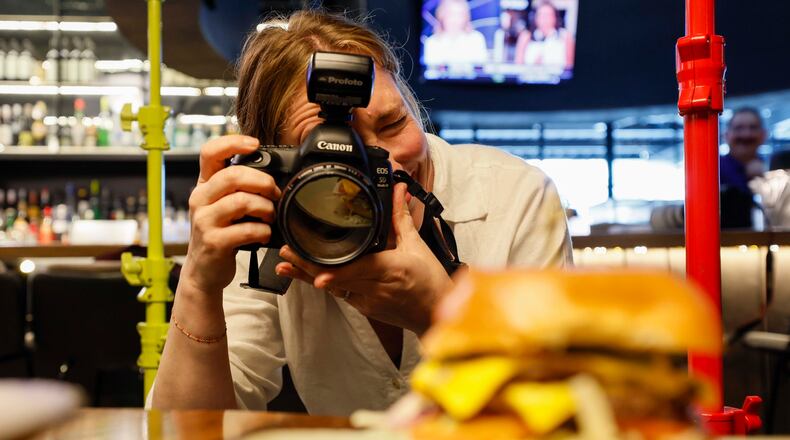 Atlanta-based lifestyle photographer Heidi Harris at work at the Painted Pickle, where she's using her own product: colorful light stands from her new company, Surrounded by Light. (Miguel Martinez/AJC)