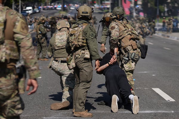 Police detain a man during a protest in the Paramount section of Los Angeles, Saturday, June 7, 2025, after federal immigration authorities conducted operations. (AP Photo/Eric Thayer)