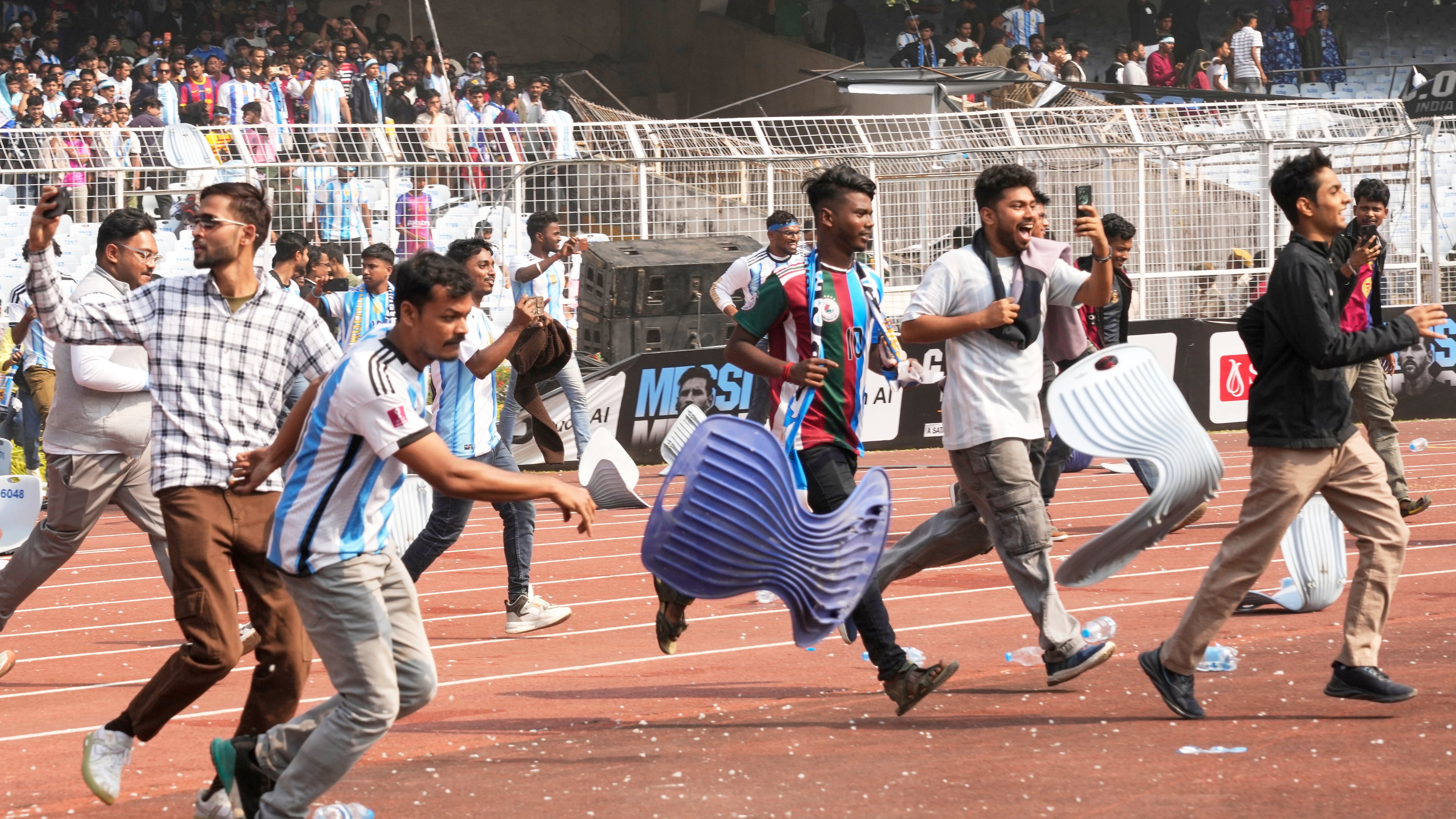 Indian fans vandalize stadium chairs as they run on to the field after failing to get a glimpse of Argentine soccer star Lionel Messi at the Salt Lake Stadium, in Kolkata, India, Saturday, Dec. 13, 2025. (AP Photo/Bikas Das)