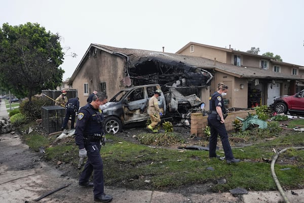 Authorities work the scene where a small plane crashed into a San Diego neighborhood, setting several homes on fire and forcing evacuations along several blocks early Thursday, May 22, 2025. (AP Photo/Gregory Bull)