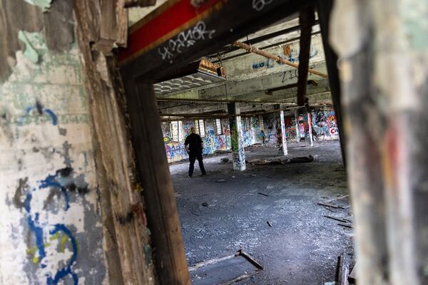 An officer walks through a building at the old prison farm during an Atlanta Police Department and Atlanta Fire Rescue media tour of the site for the proposed Atlanta Public Safety Training Center on Friday, May 26, 2023. (Arvin Temkar / arvin.temkar@ajc.com)
