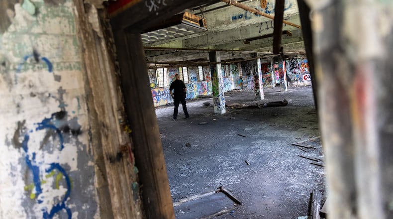 An officer walks through a building at the old prison farm during an Atlanta Police Department and Atlanta Fire Rescue media tour of the site for the proposed Atlanta Public Safety Training Center on Friday, May 26, 2023. (Arvin Temkar / arvin.temkar@ajc.com)