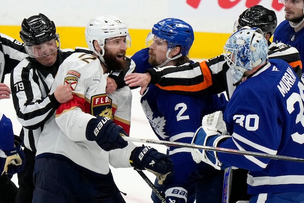 Florida Panthers' Jonah Gadjovich (12) is held back by linesman Kiel Murchison (79) as he goes after Toronto Maple Leafs goaltender Matt Murray (30) during third period NHL playoff hockey action in Toronto on Wednesday, May 14, 2025. (Frank Gunn/The Canadian Press via AP)