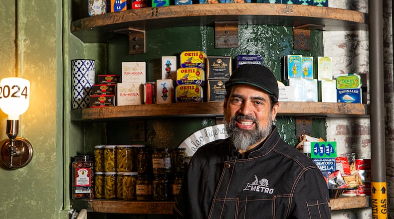 Hector Santiago, chef-owner of Spanish tapas restaurant La Metro at Ponce City Market, stands near a display of tinned seafood that is available for retail purchase. (Aaliyah Man for The Atlanta Journal-Constitution)