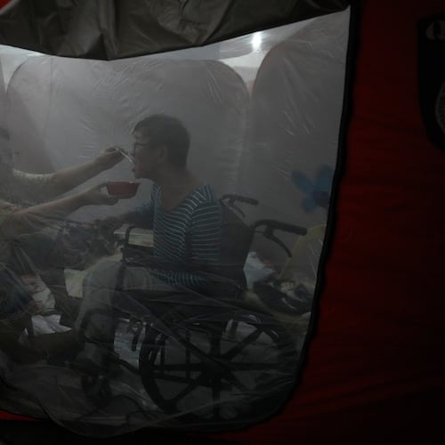 Judy Bertuso, left, feeds her husband Apollo inside a tent at an evacuation center as Typhoon Fung-wong enters the country on Sunday, Nov. 9, 2025 in Quezon city, Philippines. (AP Photo/Aaron Favila)