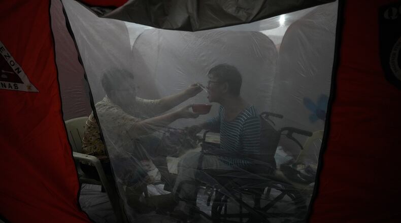 Judy Bertuso, left, feeds her husband Apollo inside a tent at an evacuation center as Typhoon Fung-wong enters the country on Sunday, Nov. 9, 2025 in Quezon city, Philippines. (AP Photo/Aaron Favila)