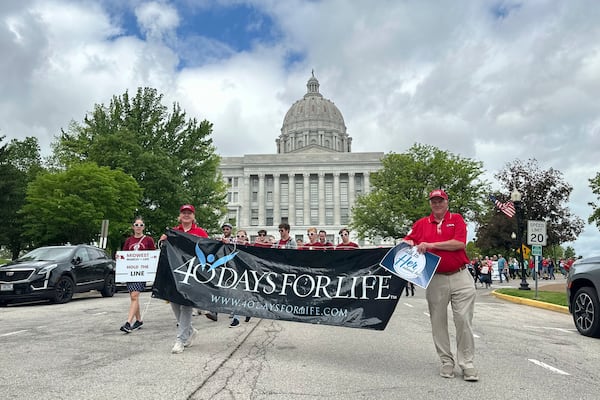 Participants in the Midwest March for Life walk through the streets of Jefferson City, Mo., with the state Capitol in the background on May 1, 2025. (AP Photo/David A. Lieb)