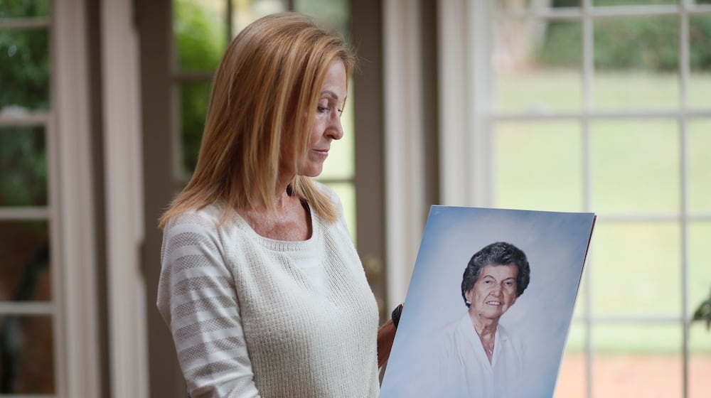 Gail Walker with a photo of her mother, Lucile McMichael Brown, who died in 2015 at age 92. Her mother was a resident of an assisted living home in Macon. Her mother apparently got up in the night and somehow went out a door that was supposed to sound an alarm to alert staff if someone opened it. But no one noticed that Brown went out the door, fell down a hill and died. She was found outside after staff noticed she was not in her room. (Bob Andres / robert.andres@ajc.com)