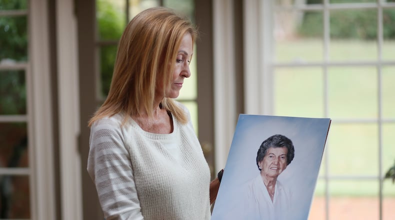 Gail Walker with a photo of her mother, Lucile McMichael Brown, who died in 2015 at age 92. Her mother was a resident of an assisted living home in Macon. Her mother apparently got up in the night and somehow went out a door that was supposed to sound an alarm to alert staff if someone opened it. But no one noticed that Brown went out the door, fell down a hill and died. She was found outside after staff noticed she was not in her room. (Bob Andres / robert.andres@ajc.com)