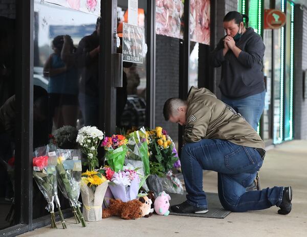 031721 Acworth: U.S. Army veteran Latrelle Rolling (left) and Jessica Lang (right) both pause to pray after dropping off flowers at Youngs Asian Massage on Wednesday, March 17, 2021, in Acworth. At least eight people were found dead at three different spas in the Atlanta area Tuesday by suspected killer Robert Aaron Long.  “Curtis Compton / Curtis.Compton@ajc.com”