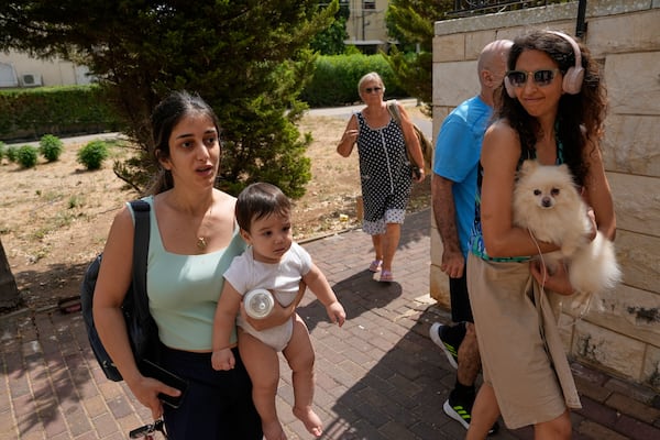 People enter bomb shelter a synagogue's bomb shelter as air raid sirens warn of incoming Iranian strikes in Haifa, Israel, Monday, June 23, 2025. (AP Photo/Baz Ratner)