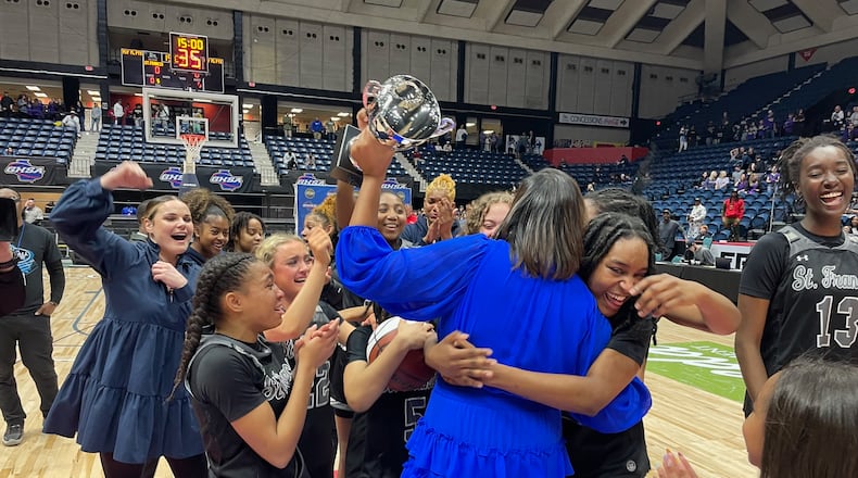 St. Francis coach Aisha Kennedy is embraced by her players after being presented the trophy for the team's 76-74 victory over Galloway in the Class A Division I girls basketball championship game at the Macon Coliseum on March 11, 2023.