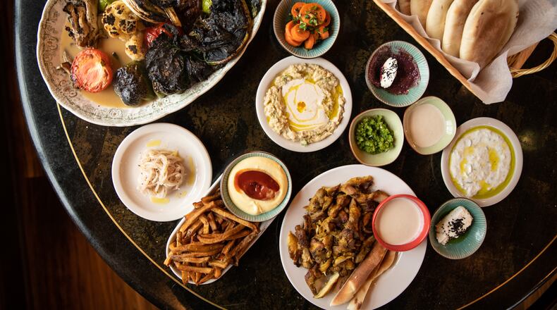 You'll be tempted to push your table space to its limits at Nur Kitchen with items such as the seasonal vegetable plate (upper left), the mezze platter (upper right) and the chicken shawarma platter (bottom) with a side of fries and mango aioli dipping sauce. (Mia Yakel for The Atlanta Journal-Constitution)