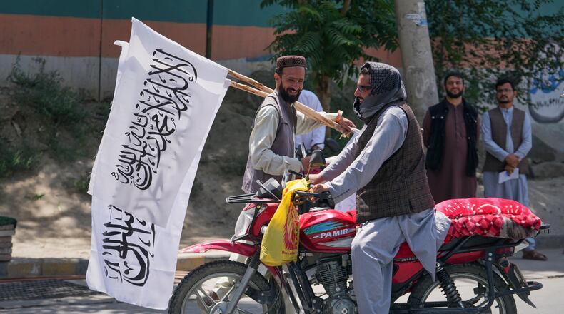 A man offers Taliban flags for sale ahead of celebrations marking the fifth anniversary of the U.S. withdrawal from Afghanistan and the start of Taliban rule, in Kabul, Afghanistan, Thursday, Aug. 13, 2026. (AP Photo/Siddiqullah Alizai)