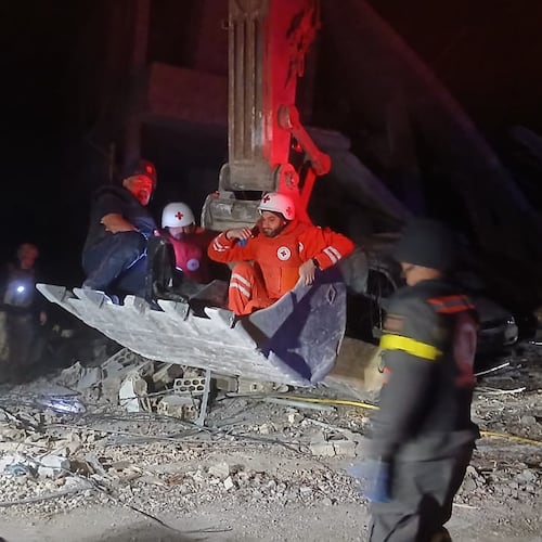 This photo released by the Lebanese Civil Defense, show Lebanese Red Cross volunteers and a Civil Defense worker sit on a excavator carrying the body of the Lebanese journalist Amal Khalil working for the daily Al-Akhbar newspaper killed in an Israeli airstrike, in al-Tiri village, south Lebanon, Wednesday, April 22, 2026. (Lebanese Civil Defense via AP)