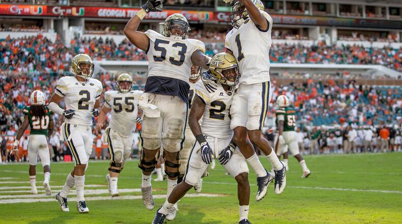 Georgia Tech Yellow Jackets running back J.J. Green (28) celebrates touchdown catch with Georgia Tech Yellow Jackets offensive lineman Jahaziel Lee (53) and Georgia Tech Yellow Jackets running back Qua Searcy (1) at Hard Rock Stadium in Miami Gardens, Florida on October 14, 2017. (Allen Eyestone / The Palm Beach Post)