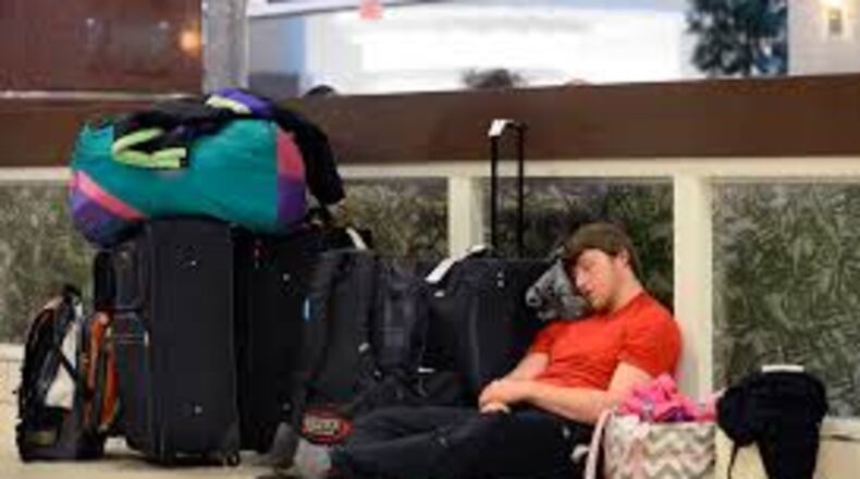 Matt Bell, of Flowery Branch, Ga., rests next to his luggage as he sits out a six-hour delay trying to get to Salt Lake City for a ski trip during an FAA-ordered ground stop at Hartsfield-Jackson International Airport when a winter storm moved into the South bringing a mix of snow, sleet and rain Wednesday, Feb. 25, 2015, in Atlanta. (AP Photo/David Tulis)