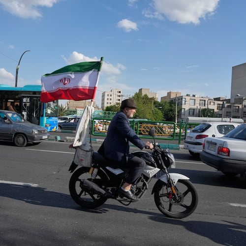 A man rides his motorbike that is adorned with an Iranian national flag, in southern Tehran, Iran, Tuesday, April 21, 2026. (AP Photo/Vahid Salemi)