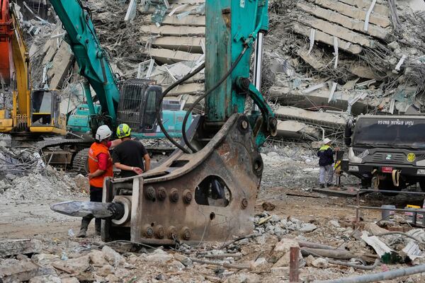 Rescuers talk as heavy machineries are employed to clear the huge pile of concrete at an under-construction high-rise building that collapsed after an earthquake in Bangkok, Thailand, Tuesday, April 1, 2025. (AP Photo/Manish Swarup)