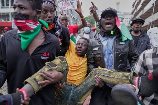 A man is carried by protesters after being beaten by anti riot police during a demonstration in downtown Nairobi, Kenya, Wednesday, June 25, 2025. (AP Photo/Brian Inganga)