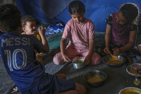 Children from the Saqr family eat lentil soup cooked by their mother at their family tent in Gaza City, Saturday, May 24, 2025. (AP Photo/Jehad Alshrafi)