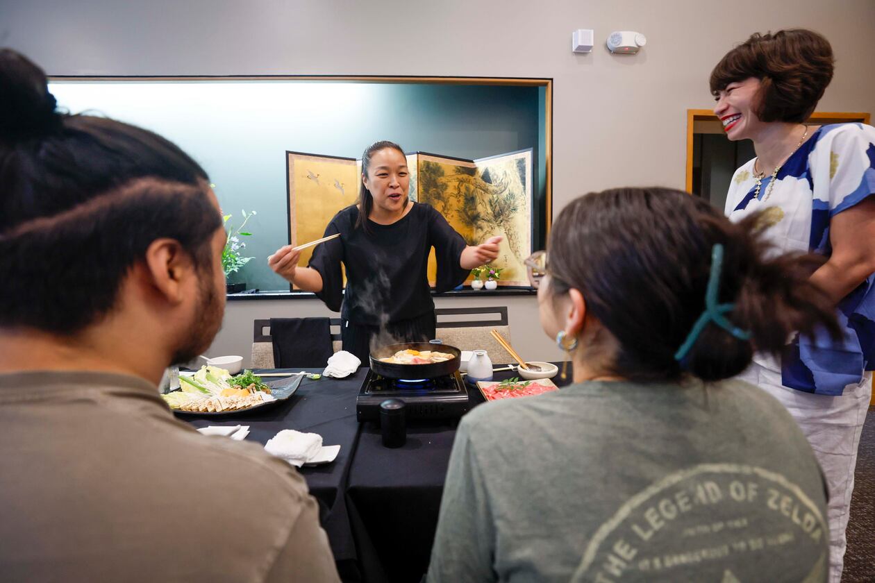 Sachiyo Nakato Takahara, owner of Nakato Japanese Restaurant, happily explains to students what the “Sukiyaki” dish is made of as Freedom University executive director Laura Emiko Soltis looks on during a celebratory dinner at Nakato restaurant in Atlanta on Sunday, Aug. 23, 2026, marking the conclusion of the virtual study abroad Japan program. (Miguel Martinez/AJC)