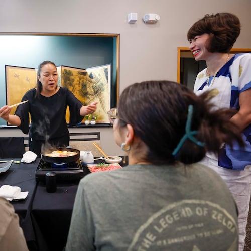 Sachiyo Nakato Takahara, owner of Nakato Japanese Restaurant, happily explains to students what the “Sukiyaki” dish is made of as Freedom University executive director Laura Emiko Soltis looks on during a celebratory dinner at Nakato restaurant in Atlanta on Sunday, Aug. 23, 2026, marking the conclusion of the virtual study abroad Japan program. (Miguel Martinez/AJC)