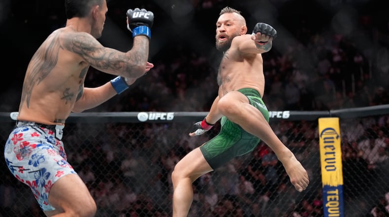 Conor McGregor, right, jumps into the air for a kick as he fights Max Holloway in a welterweight fight at the UFC 329 mixed martial arts event Saturday, July 11, 2026, in Las Vegas. (AP Photo/John Locher)