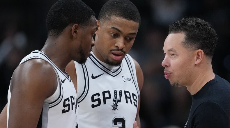 San Antonio Spurs head coach Mitch Johnson, right, talks with San Antonio Spurs guard De'Aaron Fox (4) and forward Keldon Johnson (3) during the second half of an NBA basketball game against the Sacramento Kings in San Antonio, Sunday, Nov. 16, 2025. (AP Photo/Eric Gay)