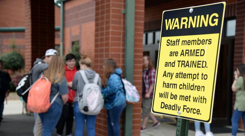 03/25/19 - Dublin -  Students wait for their parents to pick them up at East Laurens Middle-High School on Monday behind a sign that warns visitors of the school that staff members are armed with weapons to protect students. Jenna Eason for The Atlanta Journal-Constitution