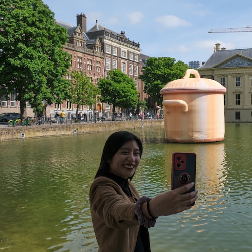 A woman takes a selfie in front of an art installation titled Like a pan in the water by Studio Job as part of the BlowUp Jubilee Art walk in the Hague, Netherlands, Thursday, May 21, 2026. (AP Photo/Patrick Post)