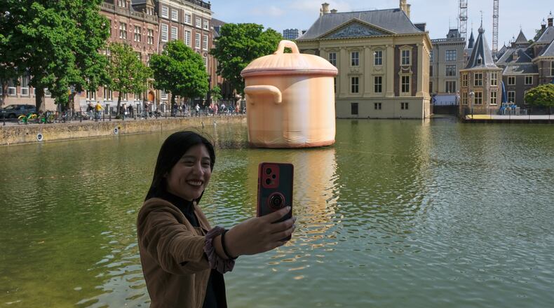 A woman takes a selfie in front of an art installation titled Like a pan in the water by Studio Job as part of the BlowUp Jubilee Art walk in the Hague, Netherlands, Thursday, May 21, 2026. (AP Photo/Patrick Post)