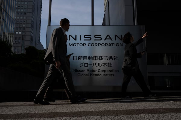 Visitors walk past Nissan signage at Nissan headquarters in Yokohama, Tuesday, May 13, 2025. (AP Photo/Louise Delmotte)