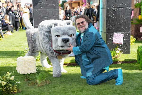 Jack Black poses for photographers with a model wolf character from the film, upon arrival at the World premiere of A Minecraft Movie on Sunday, March 30, 2025, in London. (Photo by Scott A Garfitt/Invision/AP)