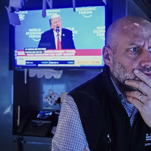 Specialist Meric Greenbaum works at his post on the floor of the New York Stock Exchange, as a television shows President Donald Trump speaking at the World Economic Forum, Wednesday, Jan. 21, 2026. (AP Photo/Richard Drew)