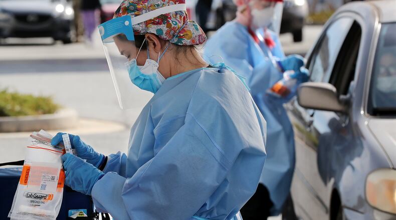 122320 Doraville: RNs Jillian Ford (left) and Elham Roshanraun (right) help gather tests at a DeKalb Board of Health testing site by the Brandsmart USA while coronavirus testing surges as Christmas nears on Wednesday, Dec. 23, 2020, in Doraville.   “Curtis Compton / Curtis.Compton@ajc.com”