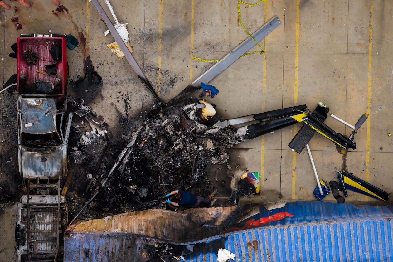 In this aerial view, people investigate the aftermath of a news helicopter crash in Chatsworth, a neighborhood in Los Angeles, on Wednesday, Sept. 16, 2026.(AP Photo/Ethan Swope)